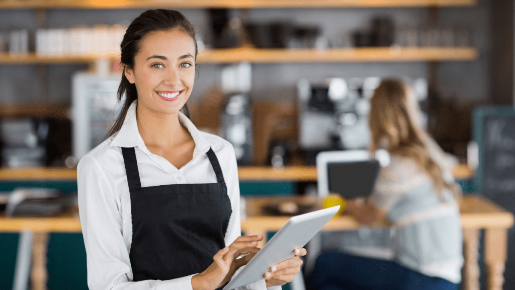 Portrait of smiling waitress using digital tablet in cafe